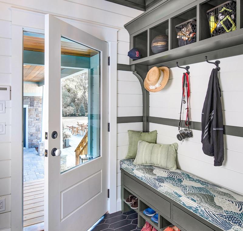 A mudroom well-equipped with hooks, overhead lighting and matching door hardware