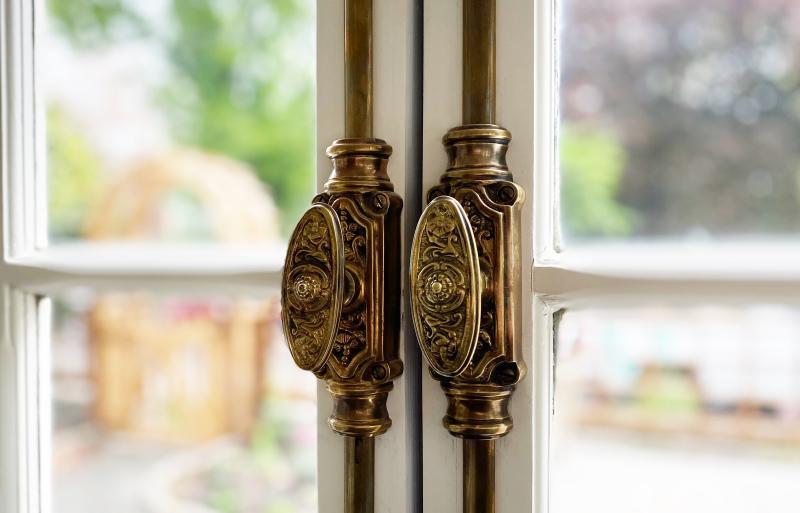 Decorative cremone bolts add old-world elegance to a pair of outs-wing casement windows 