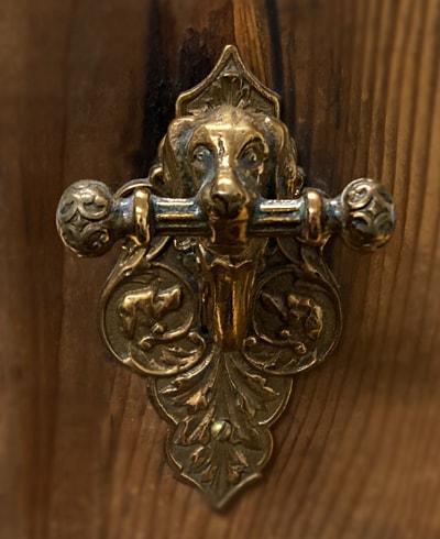 This 1870s bronze door bell featured a pull handle in the form of dog holding the cross-bar. 