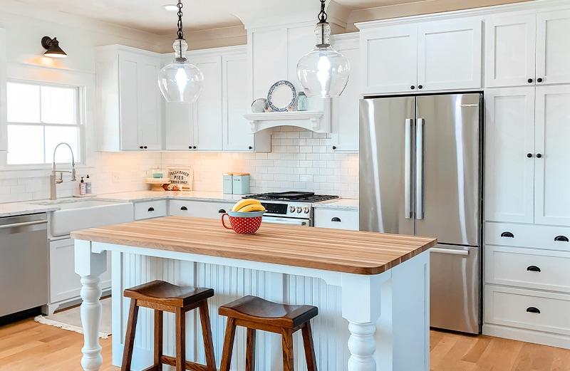 Brass cup pulls, knobs, and latches in oil-rubbed bronze add contrast to the classic all white kitchen