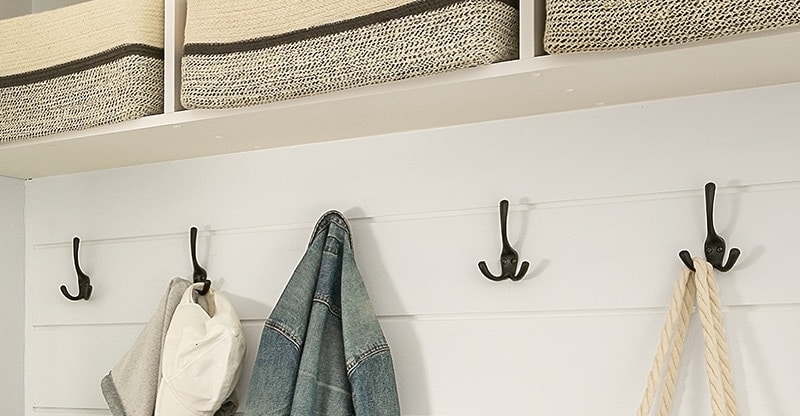 A row of sturdy three-pronged iron hooks provides plenty of hanging options in this modern mudroom.