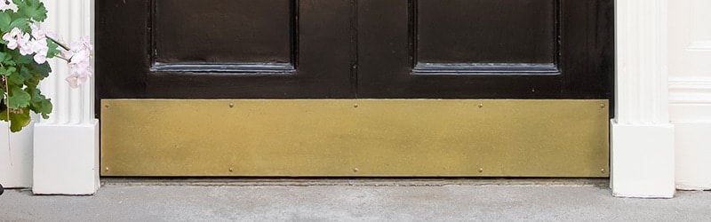 Entry door with solid brass screw mount kick plate