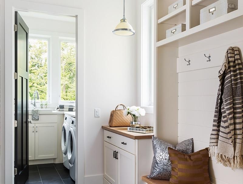 A well-organized mudroom with plenty of hooks, bins with label holders, and bright pendant lighting. 